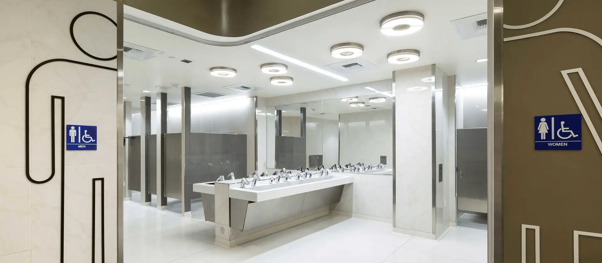 Commercial washroom with coordinated mirrors, faucets, and accessories