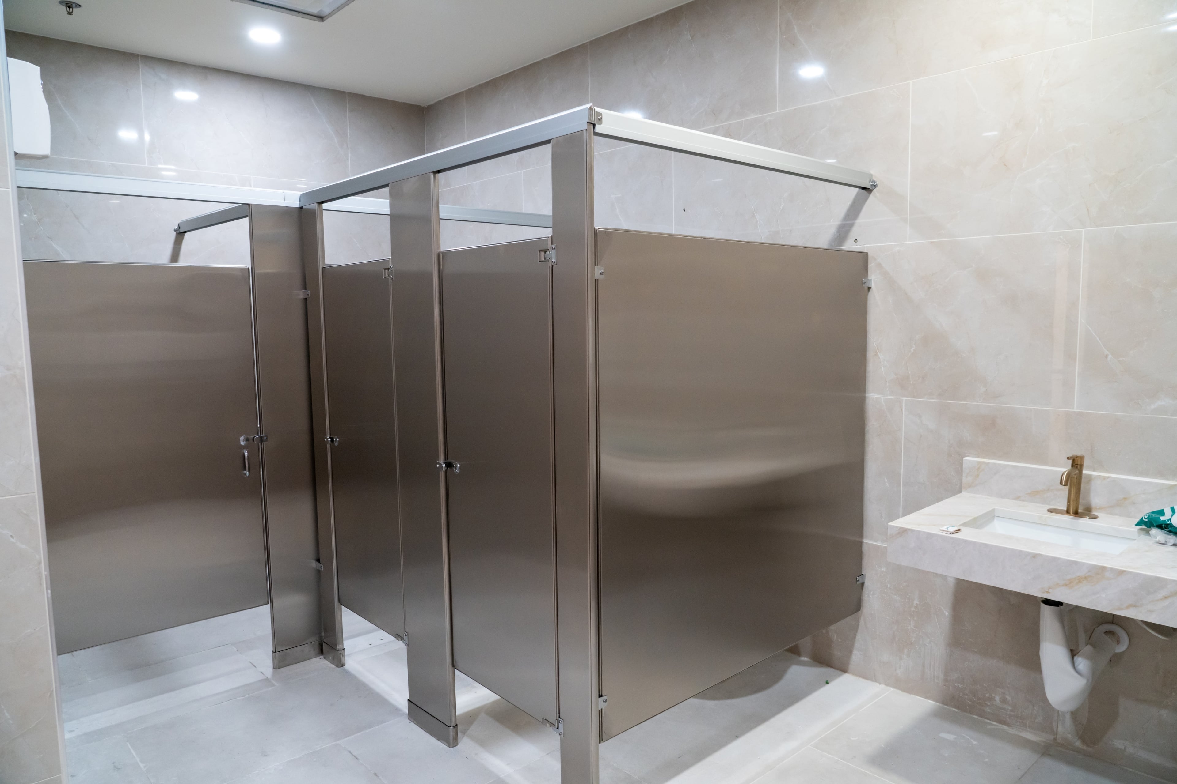 Brushed stainless steel bathroom partitions in a marble restroom in Irving, Texas